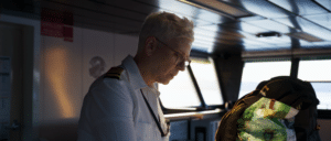 Genevieve Fritschen looks down at the desk in the pilothouse with the Puget Sound glowing through the windows behind her