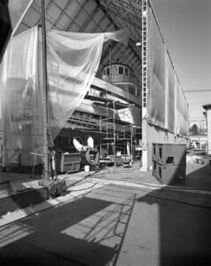 The Virginia V sits on stilts underneath a large tent with plastic draping barely revealing the open hull