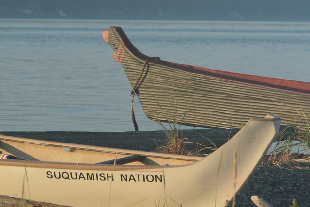 Two canoes docked side by side, with one labeled "Suquamish Nation" in black text on white paint.