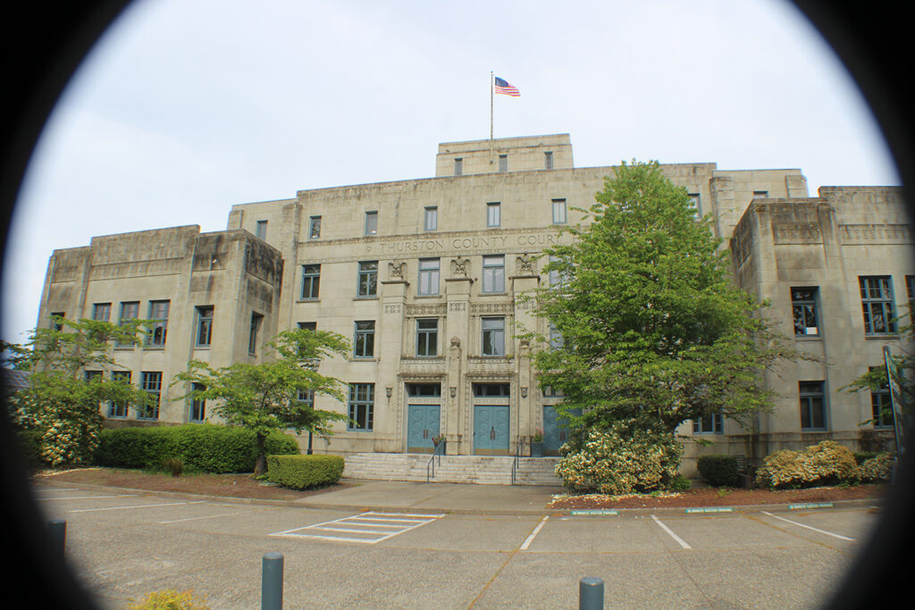 An old, beige courthouse with an American flag on its roof.
